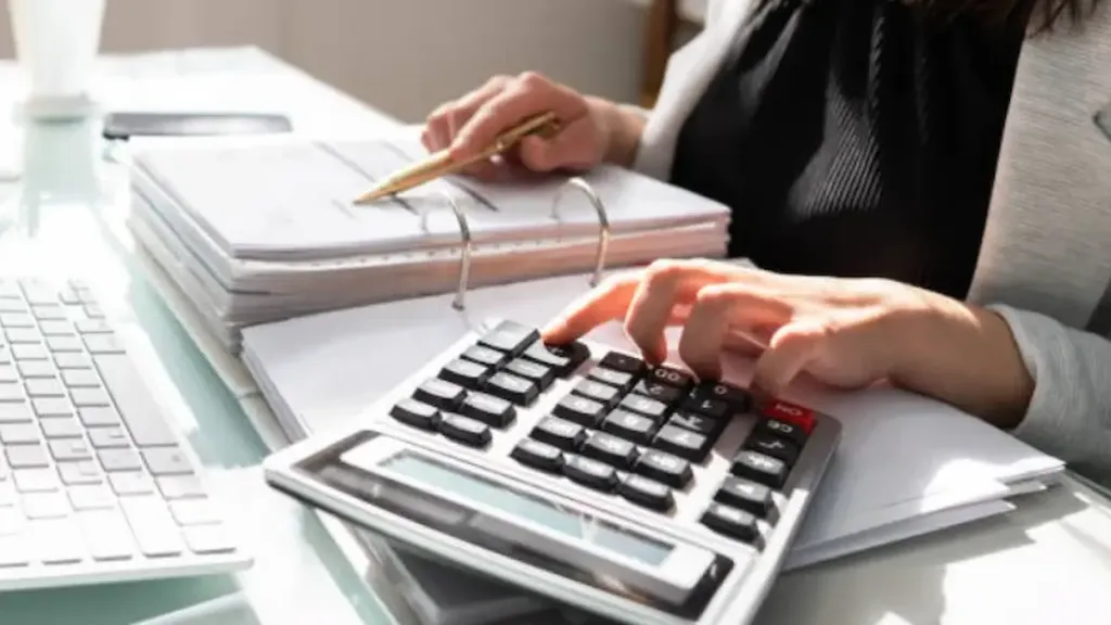 Professional accountant performing asset valuation for visa purpose in Bangladesh using calculator and documents.